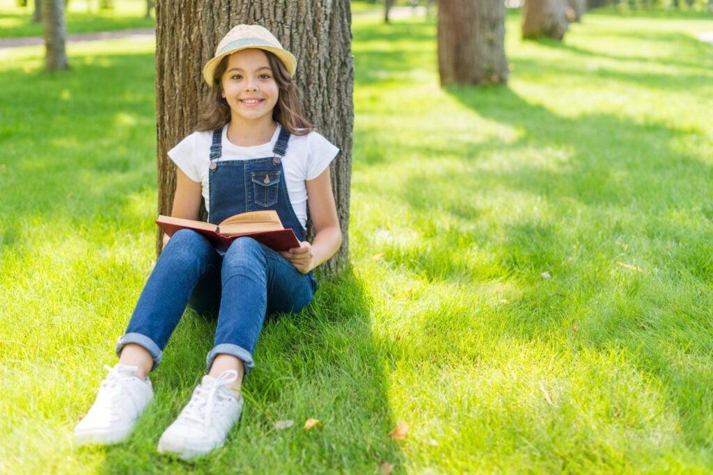 Image by <a href="https://www.freepik.com/free-photo/little-girl-reading-book-while-sitting-grass_5263659.htm#query=kid%20reading%20a%20book%20in%20park&position=8&from_view=search&track=ais">Freepik</a>